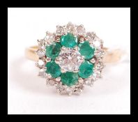 An 18ct gold emerald and diamond cluster ring having a central 20 point diamond with a halo of