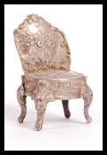 A silver hallmarked silver Dolls house chair in the form of a 19th Century French Louis XV style
