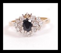 A hallmarked 9ct gold cluster ring set with a central blue sapphire surrounded by white stones.