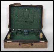 An early 20th century fitted leather suitcase with glass and silver metal vanity accoutrements