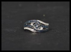 A 14ct white gold sapphire and diamond cross over ring of knot form. Weighs 3.9 grams size O.
