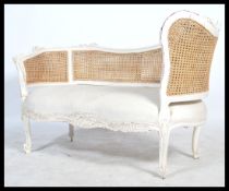 A good 20th century French window seat / loving sofa having bergere caned upright back rest, white
