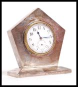 An early 20th century silver hallmarked desk top clock having a sloped base. The clock of pentagonal