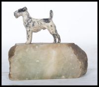 An early 20th century cold painted metal figurine of a terrier dog raised on a stone base.