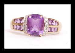 A hallmarked 9ct gold diamond and purple stone set ring. The ring having a large central cushion cut