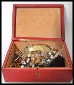 A vintage red leather and gilt tooled jewellery box opening to reveal a collection of vintage