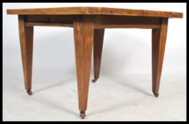 An Edwardian Arts & Crafts oak wind out extending dining table complete with winder and additional