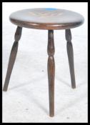 An early 20th century stained beech tripod stool having a stencilled dragon design to seat.