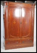 An impressive Edwardian mahogany inlaid large bow fronted double wardrobe armoire. Raised on a
