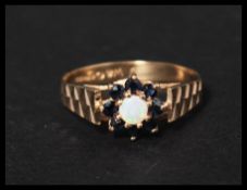 a hallmarked 9ct gold blue sapphire and opal ring set with a central opal surrounded by a sapphire