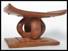 A 20th century African hardwood tribal stool / pillow neck rest having an angular seat raised on