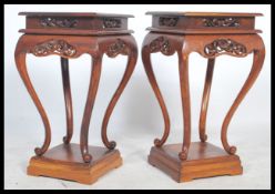 A pair of Chinese hard wood pedestals each with solid tops above carved blossoming aprons and on