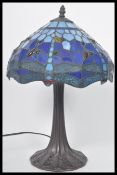 A vintage Tiffany style leaded glass table lamp having a naturalistic style base with stained