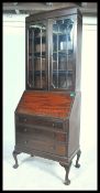 A 1920's mahogany bureau bookcase having an astragal glazed door bookcase over a fall front bureau