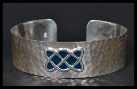 A sterling silver arts and crafts style bangle bracelet having a hammered design with an enamel