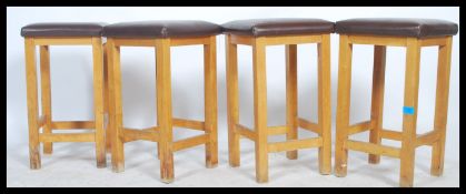 A set of four retro 1970s beech wood frame stools raised on square chamfered legs united by