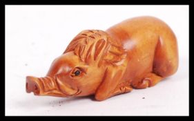 A 20th century carved Japanese netsuke in the form of a seated pig.