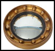 An early 20th century gilt framed ships mirror of circular form. The nautical themed mirror having