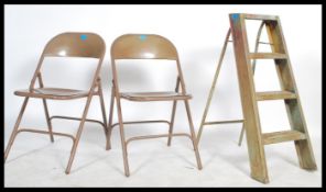 A pair of vintage mid century enamelled metal folding village hall chairs together with a small