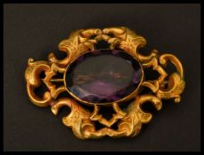 A large gold tone metal and amethyst brooch having