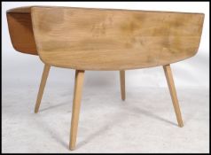 A retro mid 20th century beech and elm Ercol drop leaf dining table being raised on squared legs