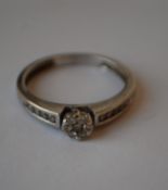 A hallmarked 9ct white gold and diamond cluster ring having a central diamond cluster with channel