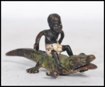 An early 20th century Austrian cold painted bronze figure of a young black boy sat upon the back