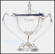 An early 20th century silver hallmarked three handledmustard pot condiment with blue glass liner