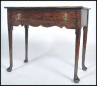 An 18th century oak lowboy side table being raised on simple turned, tapering legs with pad feet.