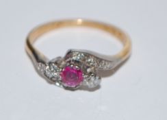 An 18ct gold and platinum ruby diamond ring set with a round cut ruby flanked by two round cut