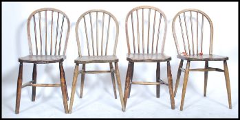 A set of four early 20th century beech and elm hoop back dining chairs in the manner of Ercol,