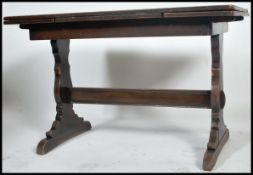 A 1930's oak draw leaf refectory dining table being raised on lyre shaped supports with stretcher