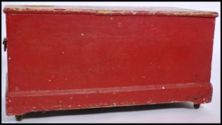 A large early 20th century pine blanket box having brass drop handles with a red painted finish. The