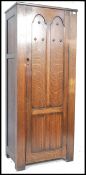 A mid century ecclesiastical hall cupboard having full length door with linen fold design opening to