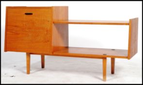 A vintage 1960's teak low sideboard media unit having a large angled drop down door adjacent to a