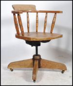 An Edwardian Industrial office swivel desk chair having spindle gallery, saddle seat with shaped
