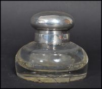 An early 20th century silver hallmarked topped cut glass desk top inkwell having a faceted glass