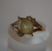 A hallmarked 9ct gold ring  set with a central cushion cut pale yellow stone having stylised diamond