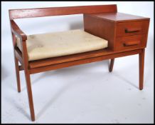 A retro mid century teak wood Danish inspired telephone table with padded seat and being raised on