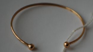 A hallmarked 9ct gold bangle with ball finials. Hallmarked Birmingham. Weight 2.5g.