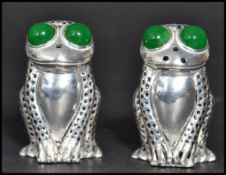 A pair of continental silver novelty pepper and salt pots in the form of frogs with green stone