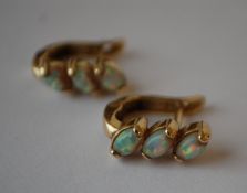 A pair of 14ct gold and opal earrings being set with three oval opal cabochons. Marked 585, tests