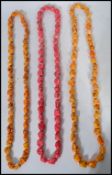 A group of three large and heavy painted stone necklaces. The stones of varying form and sizes.