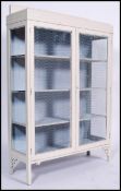A 1920's shabby chic painted display cabinet having mesh doors with shelved interior being raised on