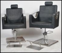 A pair of contemporary retro style minimalist chrome salon chairs being raised on chrome bases
