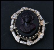 A 19th century Victorian carved glass cameo brooch in an amethyst purple colour with silver white