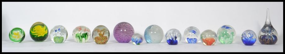 A collection of fourteen 20th century glass paper weights to include Caithness, control bubble etc