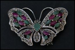 A sterling silver marcasite brooch in the form of a butterfly having ruby and emerald adorned wings.