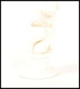 A Royal Doulton white glazed figurine of a crouching female nude designed by Leslie Harradine.