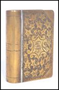 A 19th century Victorian brass snuff box in the form of a book having an engraved leaf design with